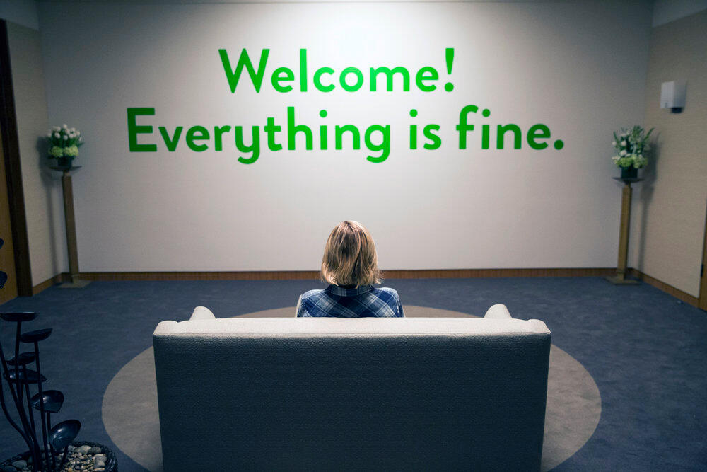 A screencap of Eleanor facing a wall at the Good Place which reads: Welcome! Everything is fine.